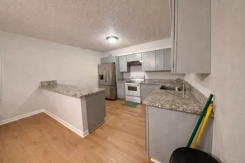 a kitchen with kitchen island granite countertop a sink stove and refrigerator