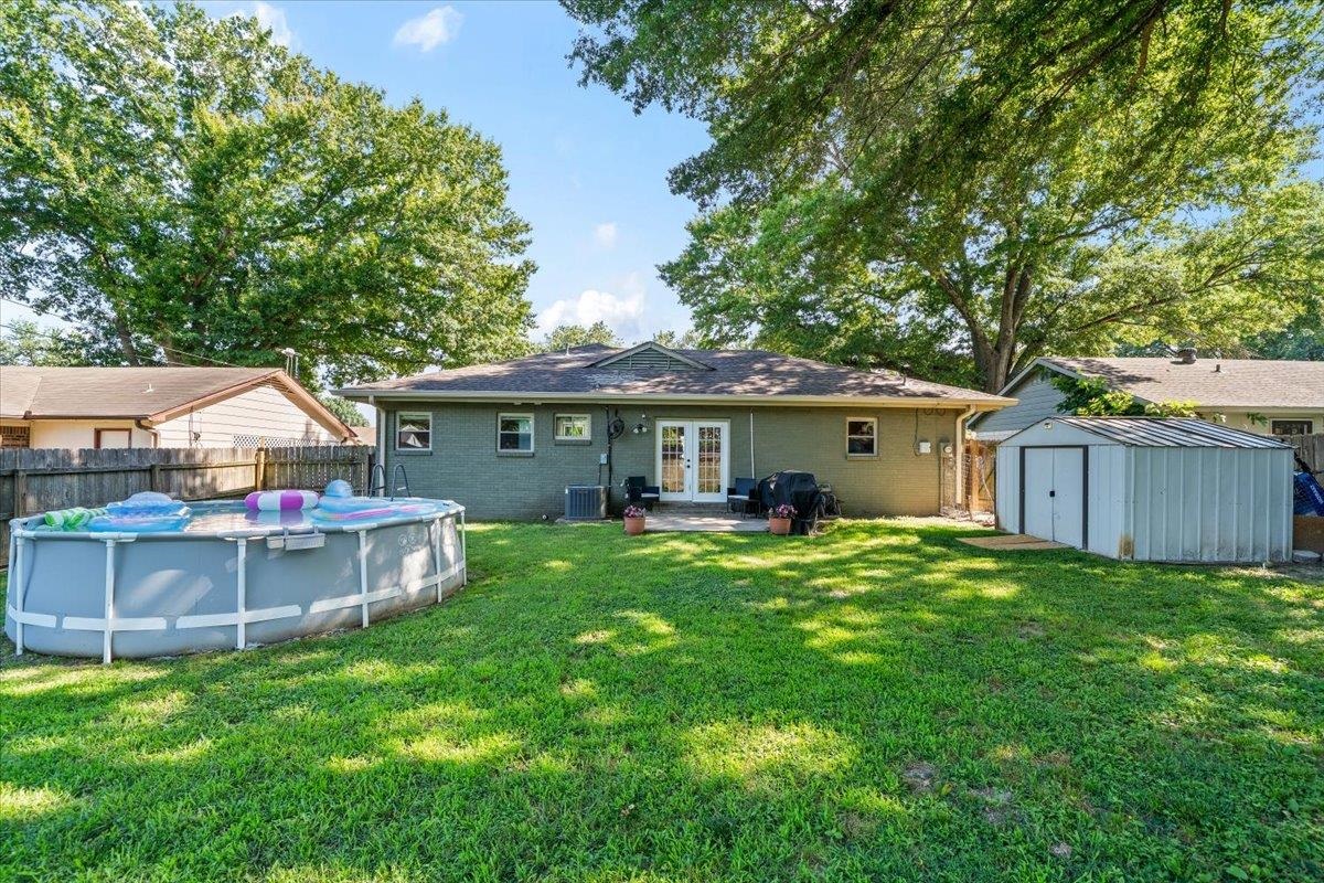 4686 Bill Knight Road Millington, TN 38053 - Photo 29 of 29 Expansive backyard featuring a lush lawn, mature trees, an above-ground pool, a patio area, and a metal storage shed