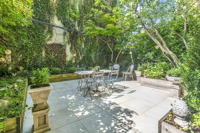 a view of a patio with table and chairs potted plants and large tree