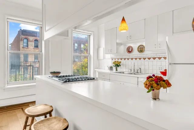 a white kitchen with a sink a stove a dining table and chairs