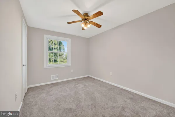 an empty room with ceiling fan and window