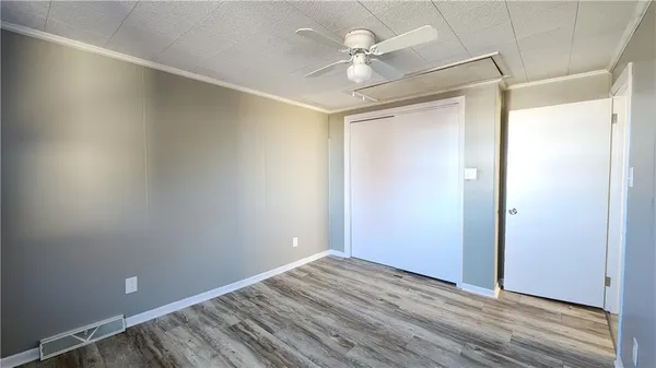 an empty room with wooden floor and fan