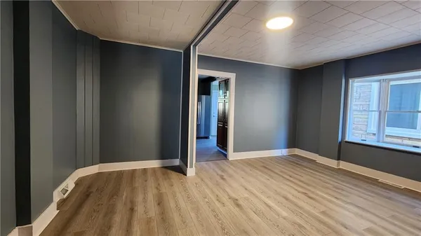 a view of an empty room with window and wooden floor