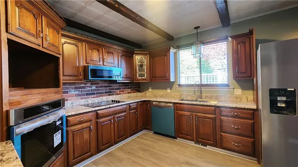 a kitchen with stainless steel appliances granite countertop wooden cabinets stove top oven and sink