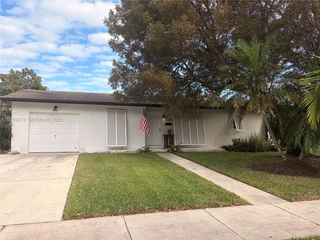 a front view of a house with a garden and trees