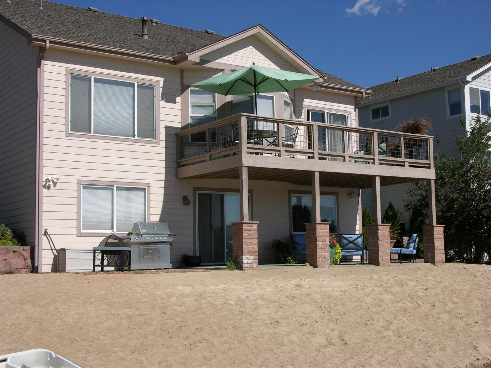 Rear of house faces the lake, with a sandy beach and boat dock