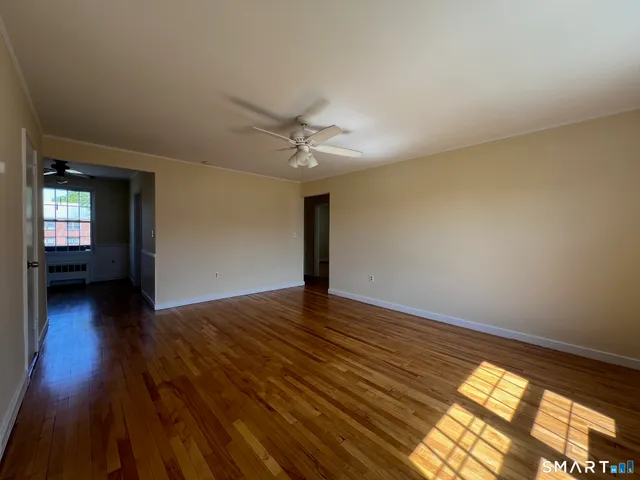 a view of a livingroom with wooden floor and a ceiling fan