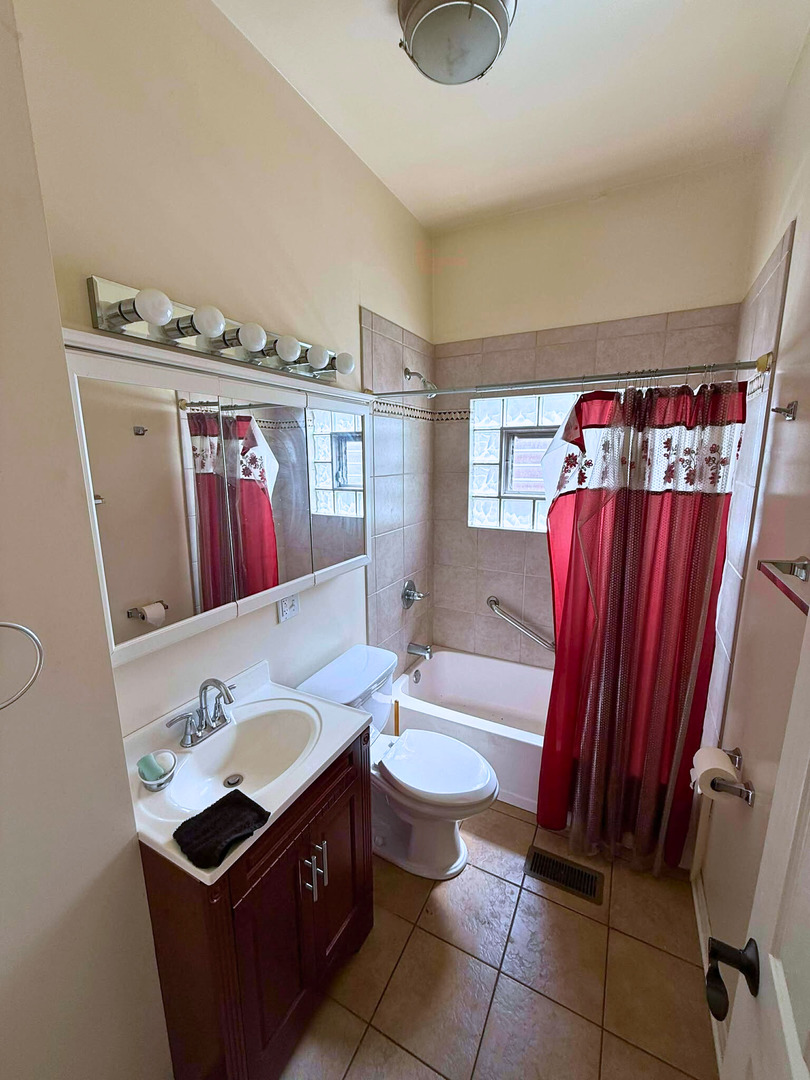 2038 West 70th Place Chicago, IL 60636 - Photo 5 of 8 a bathroom with a sink a toilet and a mirror