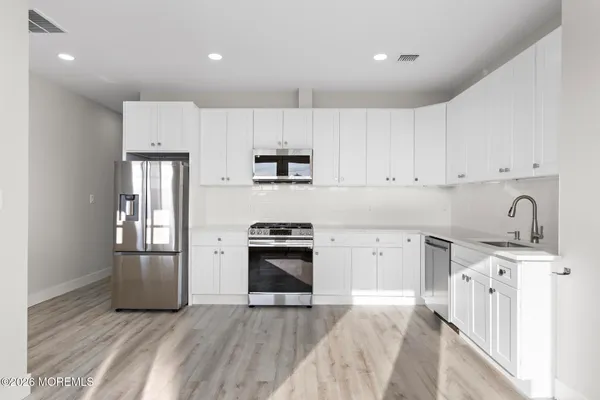 a kitchen with granite countertop white cabinets and stainless steel appliances