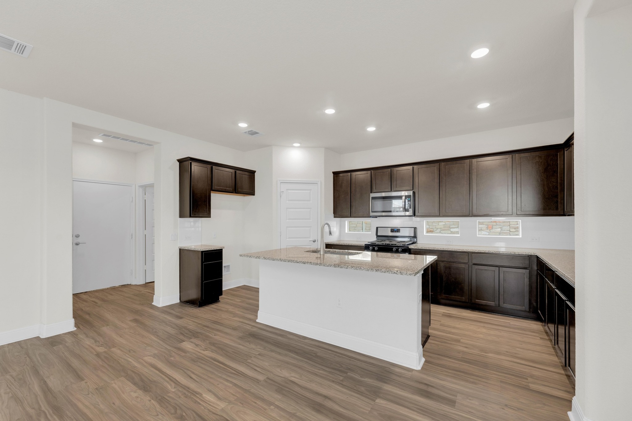 16817 Ponte Cove Pflugerville, TX 78660 - Photo 10 of 36 a kitchen with stainless steel appliances kitchen island granite countertop a sink and a microwave