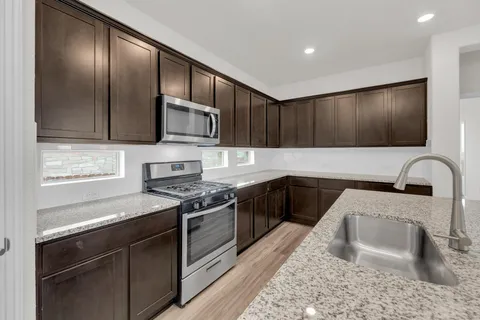 a kitchen with stainless steel appliances granite countertop a sink dishwasher a stove top oven a refrigerator with island and chairs