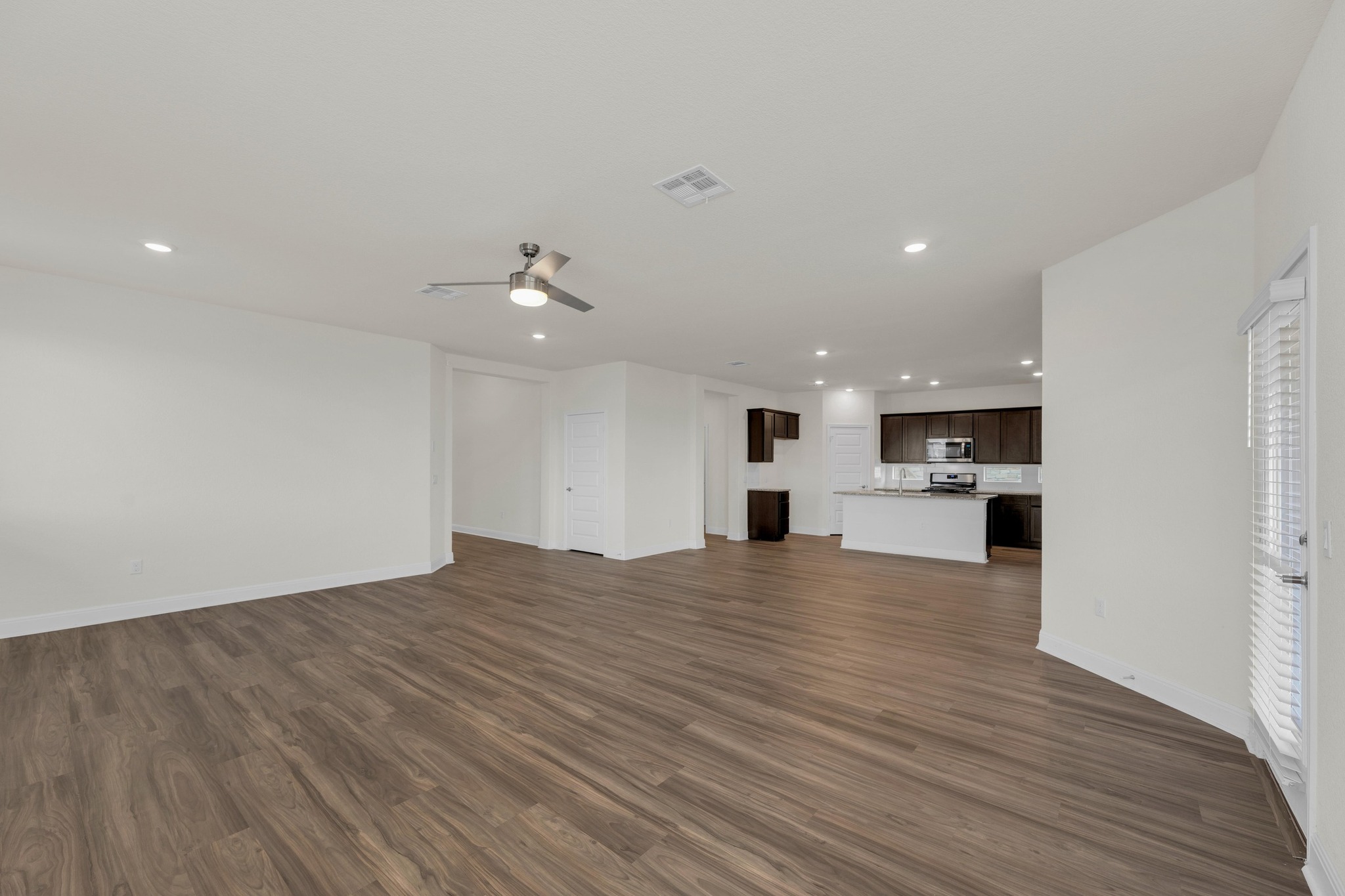 16817 Ponte Cove Pflugerville, TX 78660 - Photo 9 of 36 a view of an empty room with wooden floor and kitchen view