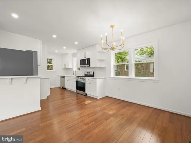 a large kitchen with cabinets wooden floor and stainless steel appliances
