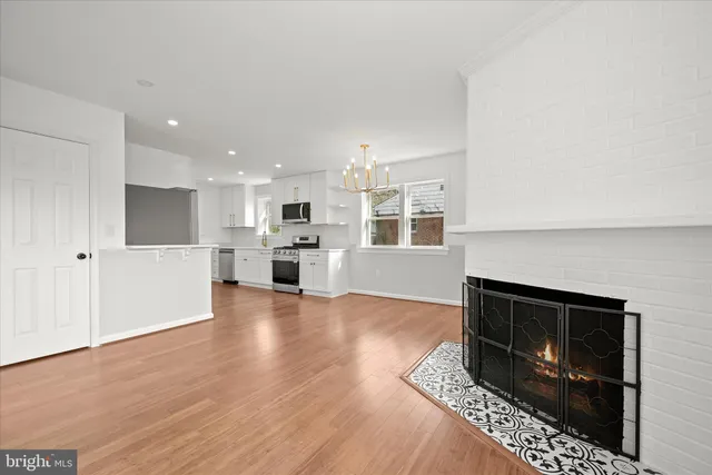 a kitchen with stainless steel appliances granite countertop a stove top oven a sink dishwasher and a refrigerator with wooden floor