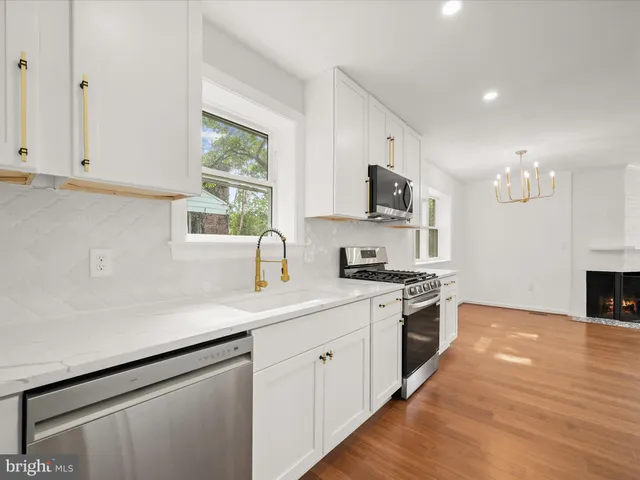 a kitchen with stainless steel appliances white cabinets a sink and a stove