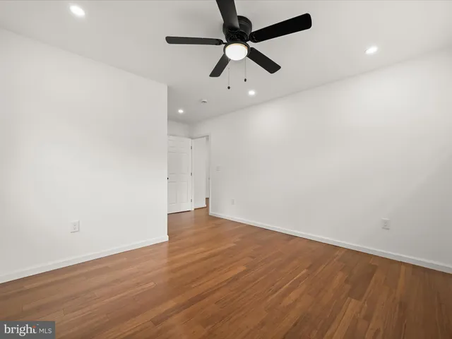 an empty room with wooden floor ceiling fan and window