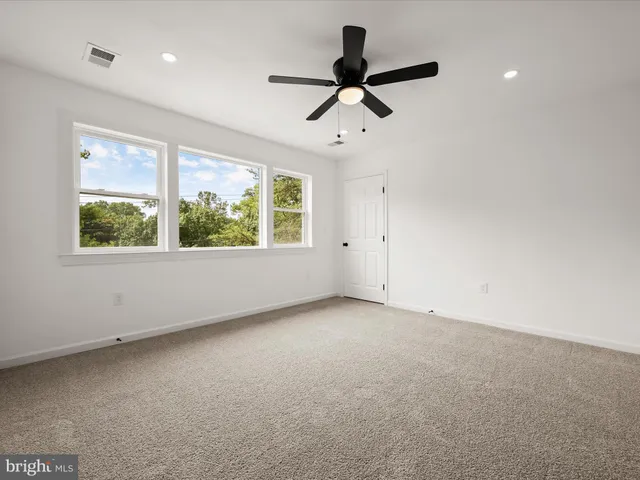 a view of a big room with a ceiling fan and windows