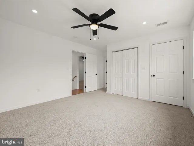 an empty room with ceiling fan and window