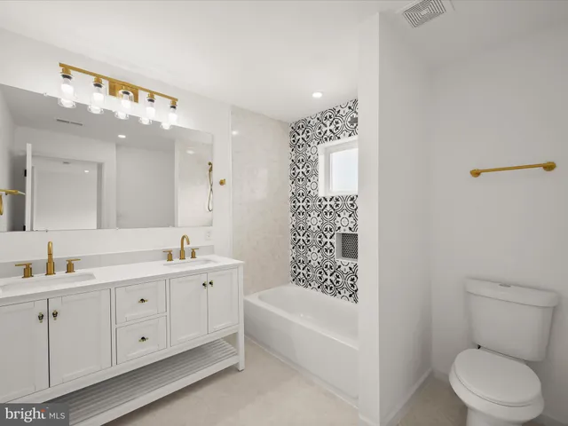 a bathroom with a double vanity sink toilet and bathtub