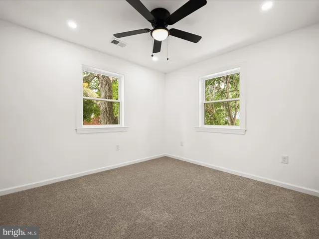 an empty room with windows and ceiling fan