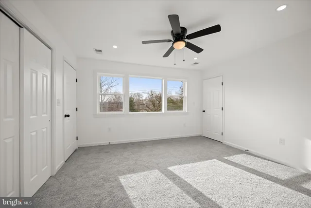 a view of empty room with window and ceiling fan