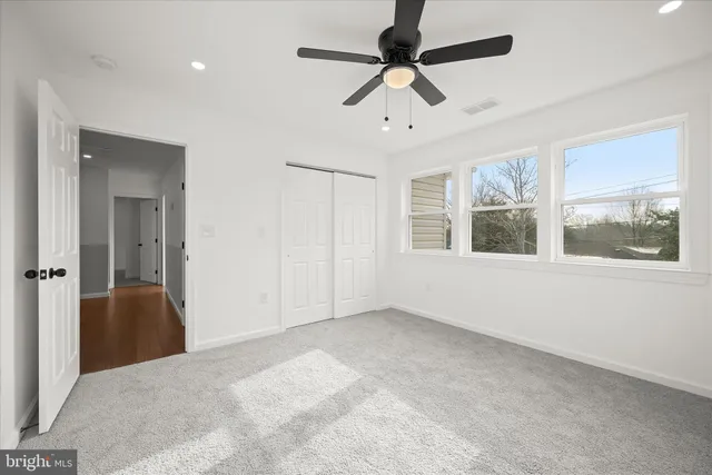 en empty room with windows and ceiling fan