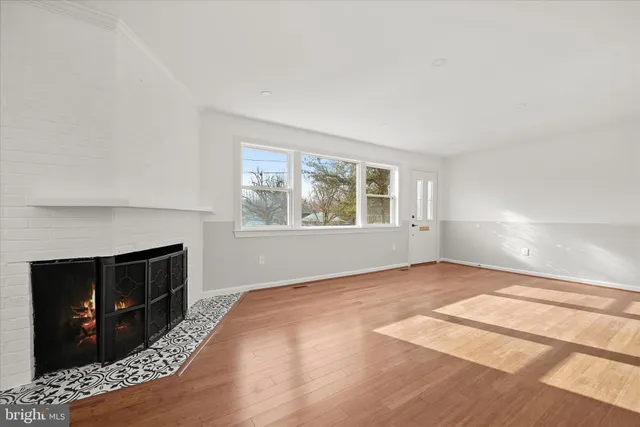 a view of empty room with a fireplace and wooden floor