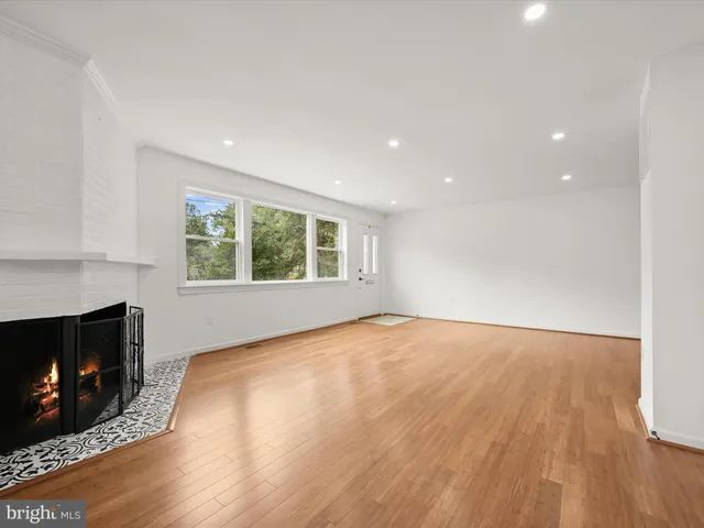a view of an empty room with wooden floor and a fireplace