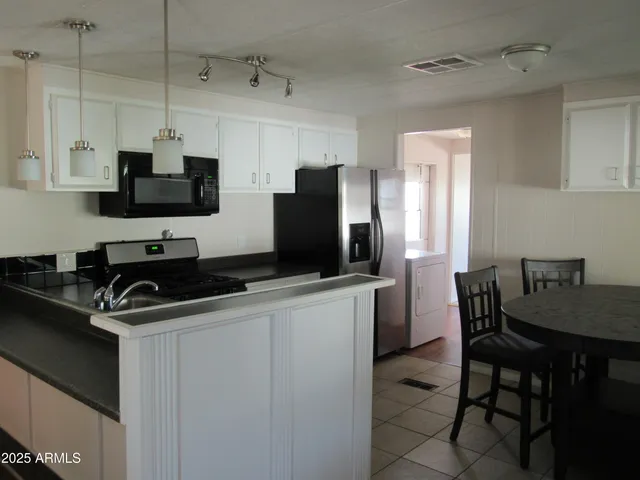 a kitchen with stainless steel appliances a stove a sink a microwave a refrigerator and cabinets