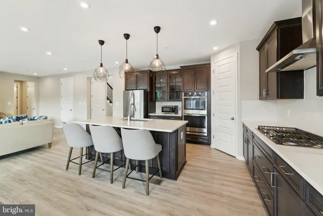 a kitchen with stainless steel appliances a kitchen island hardwood floor sink stove dining table and chairs