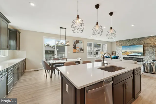 a kitchen with a stove a kitchen island a sink dishwasher a dining table and chairs with wooden floor