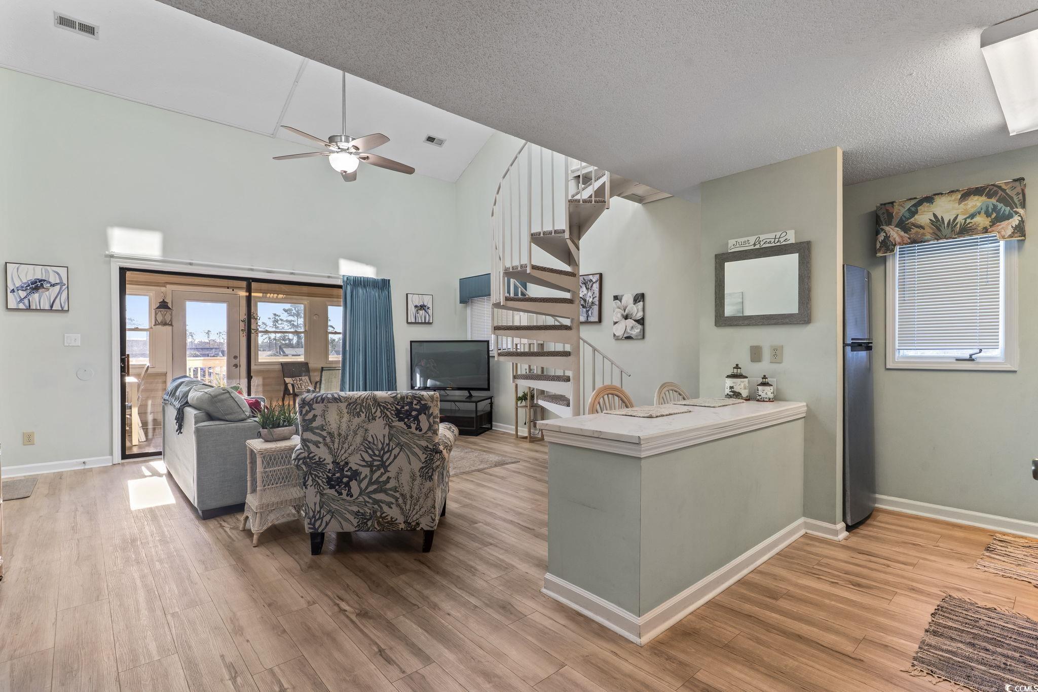 207 Double Eagle Drive, Unit F3 Myrtle Beach, SC 29575 - Photo 11 of 40 Living area featuring stairs, light wood-type flooring, a ceiling fan, a textured ceiling, and high vaulted ceiling