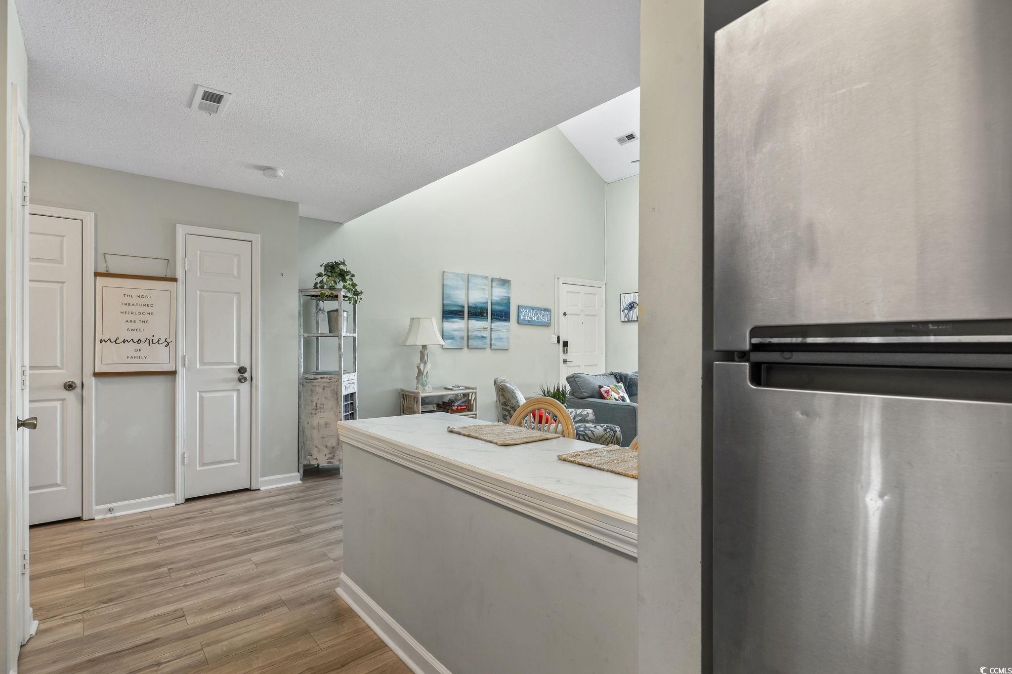 207 Double Eagle Drive, Unit F3 Myrtle Beach, SC 29575 - Photo 12 of 40 Kitchen featuring freestanding refrigerator, light wood-type flooring, a textured ceiling, and light countertops