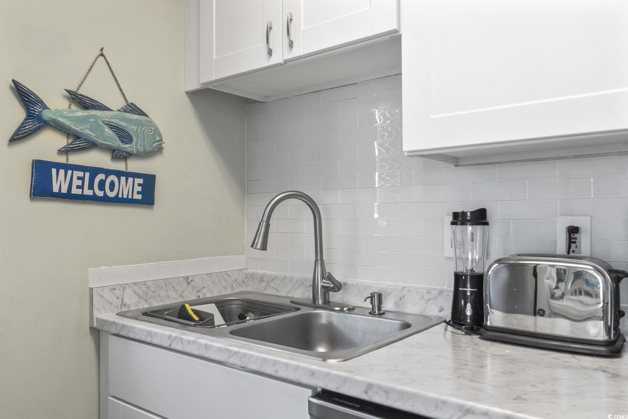 207 Double Eagle Drive, Unit F3 Myrtle Beach, SC 29575 - Photo 14 of 40 Kitchen featuring decorative backsplash, light countertops, and white cabinetry