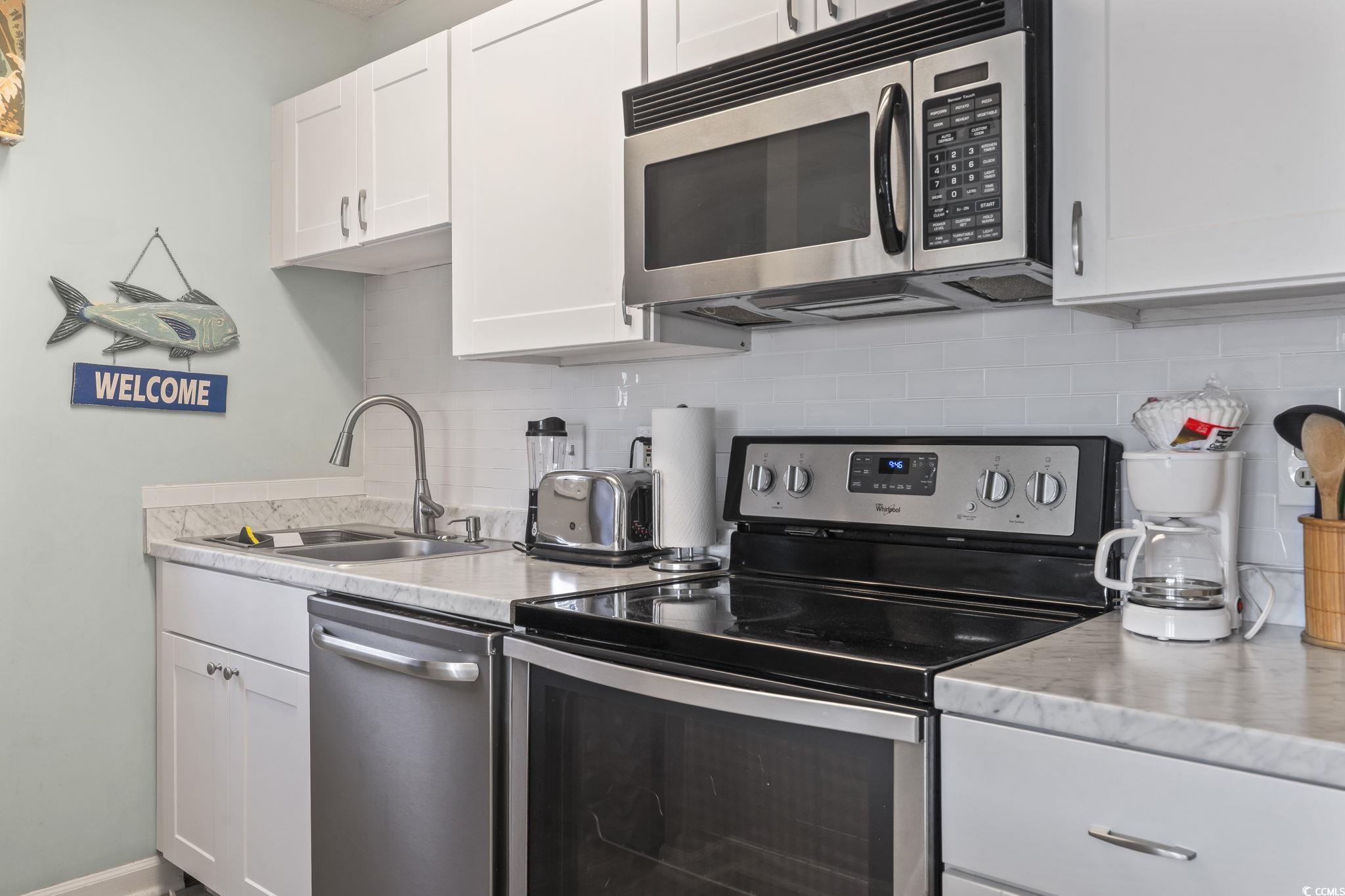207 Double Eagle Drive, Unit F3 Myrtle Beach, SC 29575 - Photo 15 of 40 Kitchen with stainless steel appliances, light countertops, white cabinetry, and tasteful backsplash