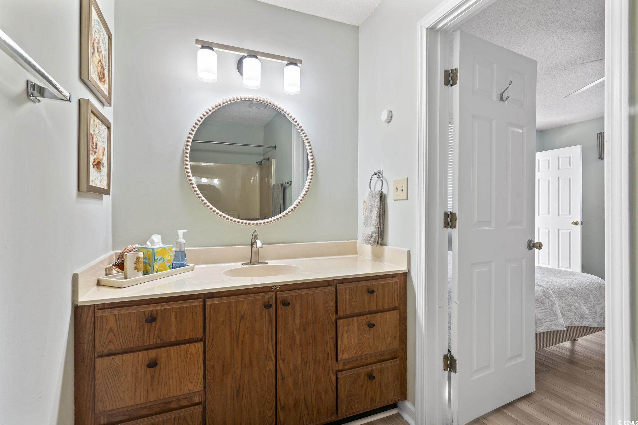 207 Double Eagle Drive, Unit F3 Myrtle Beach, SC 29575 - Photo 32 of 40 Full bath featuring vanity, a shower with shower curtain, a textured ceiling, light wood-type flooring, and connected bathroom