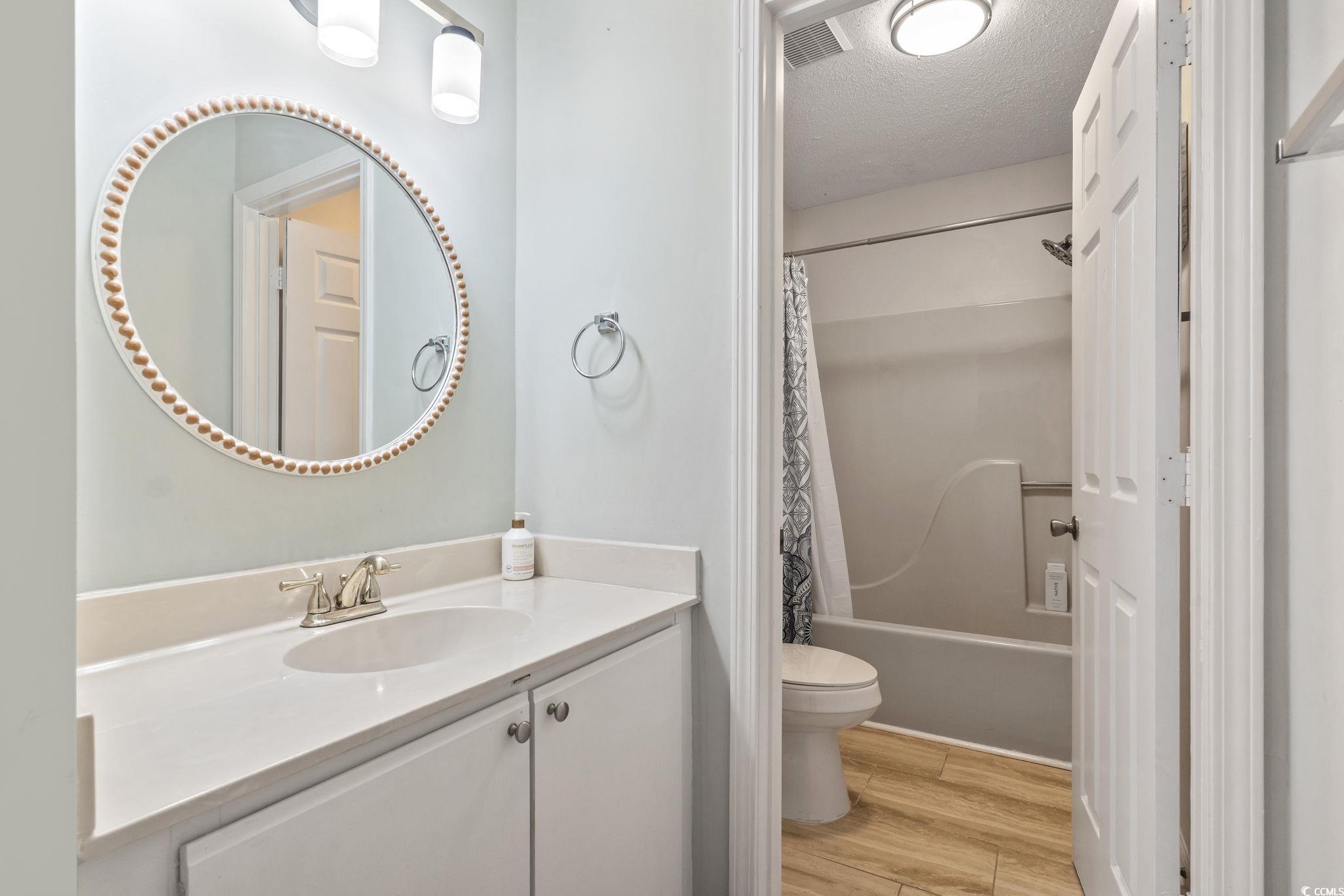 207 Double Eagle Drive, Unit F3 Myrtle Beach, SC 29575 - Photo 38 of 40 Full bath featuring vanity, shower / tub combo with curtain, light wood-type flooring, and a textured ceiling