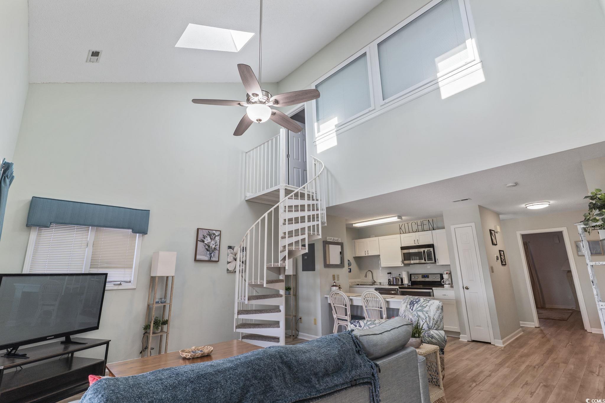 207 Double Eagle Drive, Unit F3 Myrtle Beach, SC 29575 - Photo 7 of 40 Living room featuring stairway, a ceiling fan, light wood finished floors, a skylight, and a high ceiling