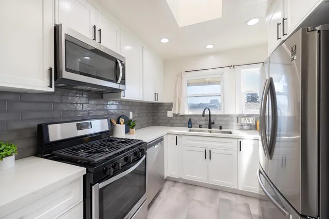 a kitchen with stainless steel appliances a sink a stove a microwave and refrigerator