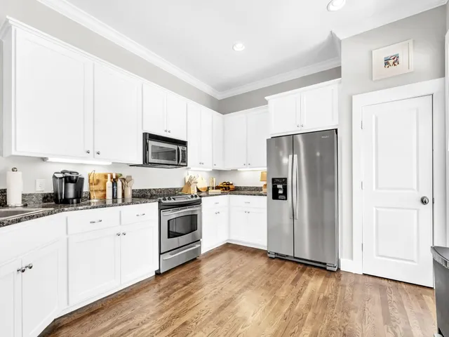 a kitchen with granite countertop white cabinets and stainless steel appliances