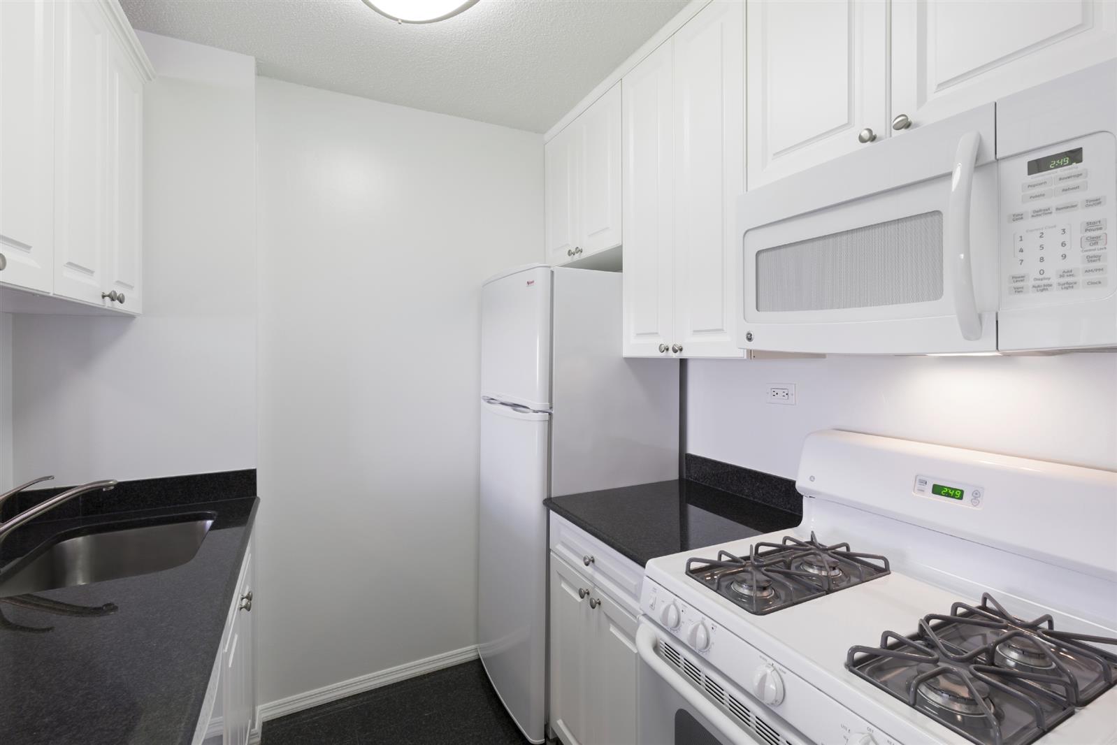 155 East 31st Street, Unit W8F Manhattan, NY 10016 - Photo 2 of 10 a kitchen with a stove and wooden cabinets