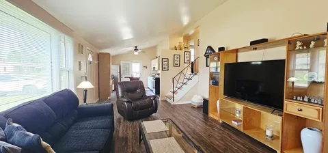 a living room with furniture a flat screen tv and a floor to ceiling window