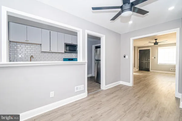 a kitchen with stainless steel appliances granite countertop a refrigerator a sink and white cabinets with wooden floor