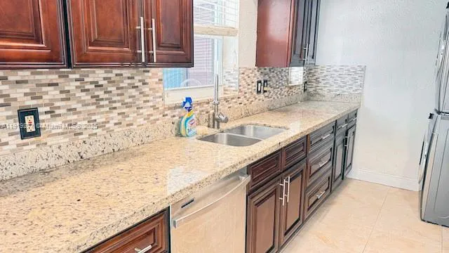 a kitchen with granite countertop a sink and a refrigerator