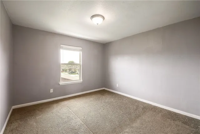 an empty room with a window and mirror fan
