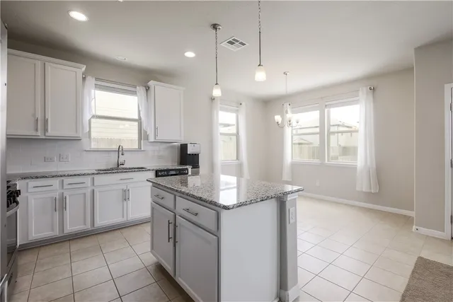 a kitchen with granite countertop a sink window and cabinets