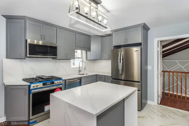 a kitchen with stainless steel appliances a sink a stove a refrigerator cabinets and a dining table