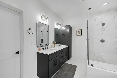 a bathroom with a double vanity sink mirror and shower