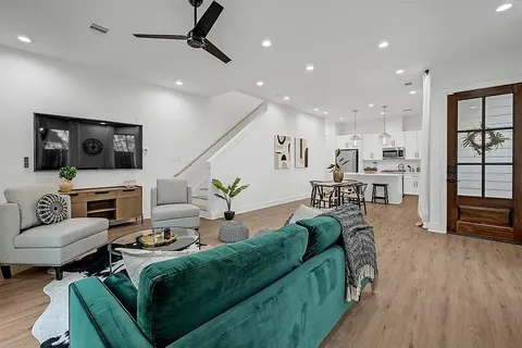 a living room with furniture kitchen view and a wooden floor