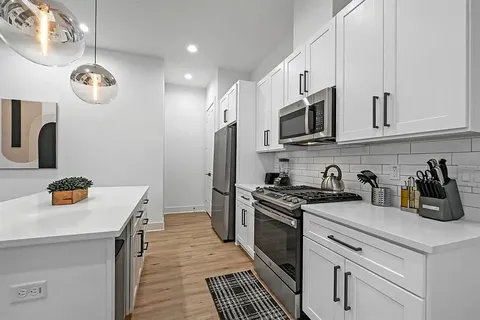 a kitchen with stainless steel appliances granite countertop a sink a stove and cabinets